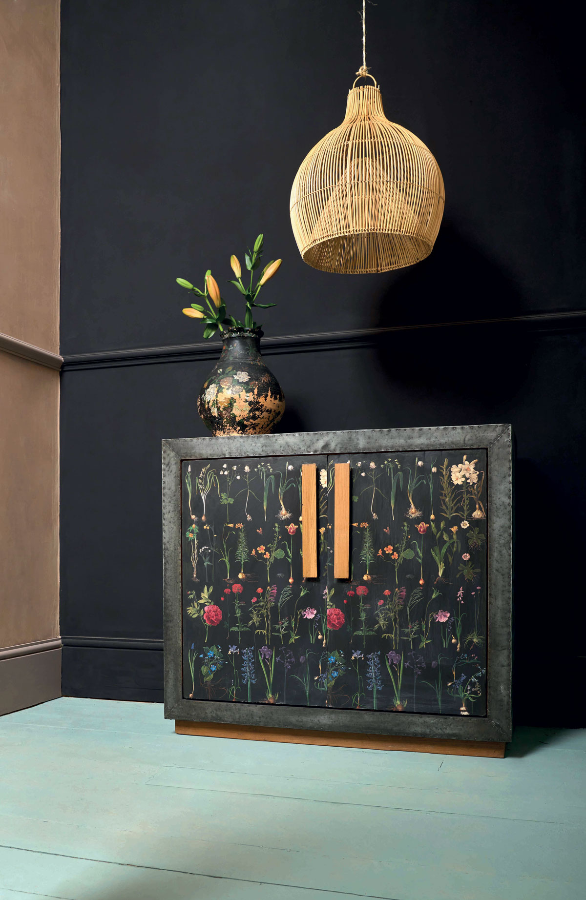 Čierna skrinka so zdobenými dvierkami s kvetinovým vzorom a výraznými zlatými úchytkami