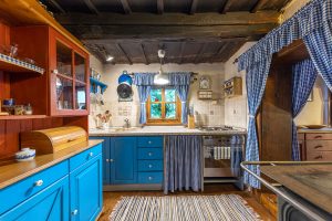 modrá kuchynská zostava s modrými károvanými závesmi v tradičnej drevenici