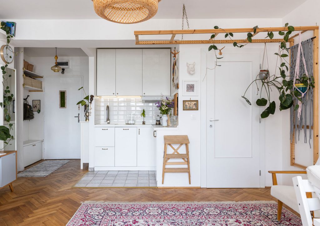 retro interiér, v ktorom je kuchyňa od obývacej izby oddelená závesným dreveným skladacím rebríkom, na ktorom sú kvetiny