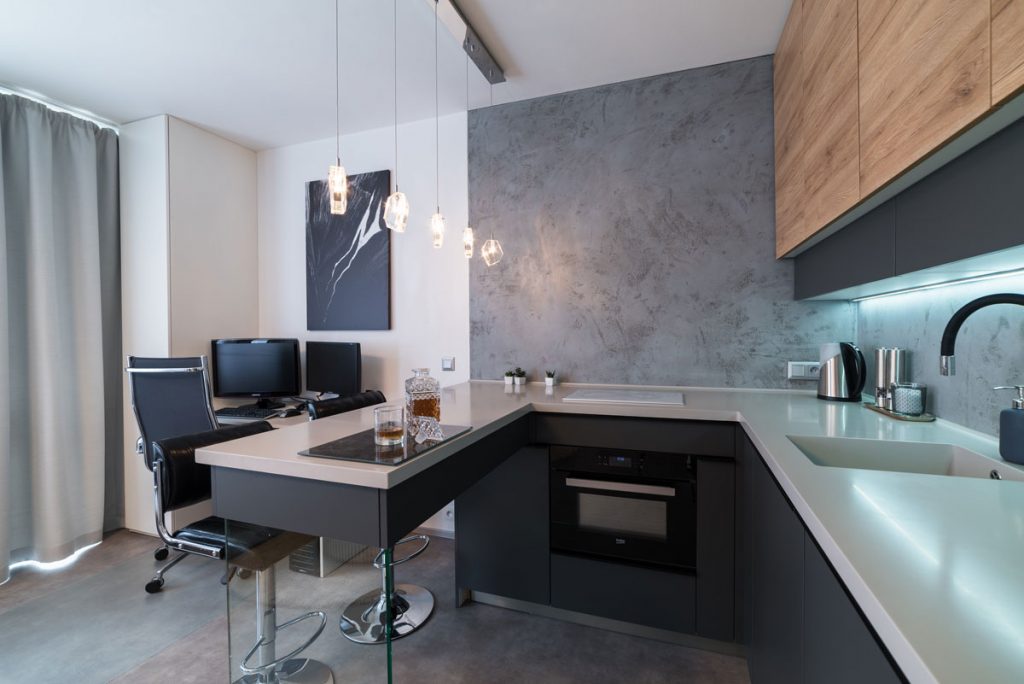 moderná minimalistická kuchyňa v garsónke s jedálenským pultom a kuchynskou zostavou v odtieňoch šedej
