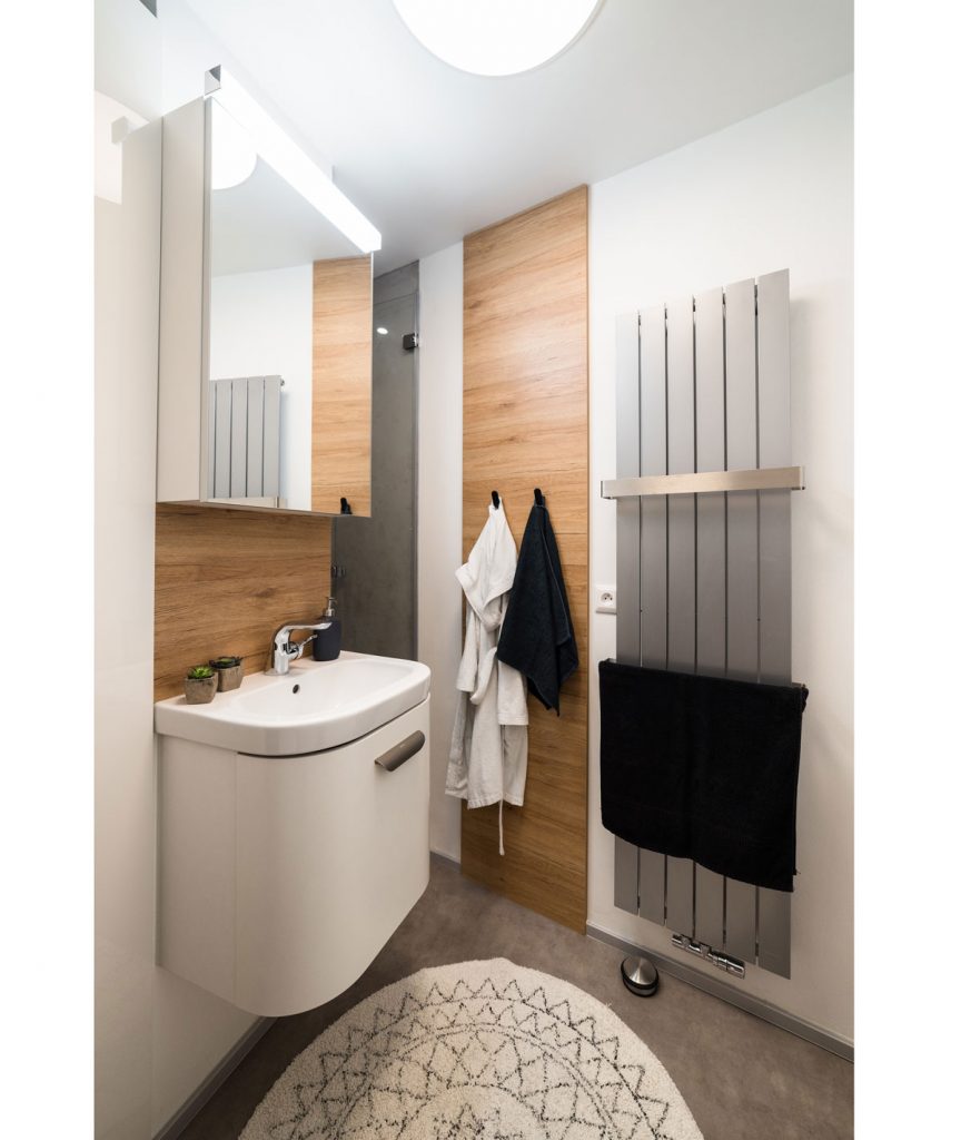 kúpeľňa v garsónke so závesným umývadlom, radiátorom na osušky a drevenými prvkami