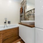 malá kúpeľňa zariadená asymetrickou vaňou, skrinkami, umývadlom a s obkladom v kombinácii bielej farby a geometrického vzoru