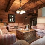 Obývačka v drevenici vo vidieckom štýle s páskovanou sedacou súpravou a truhlicovým stolíkom