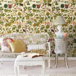 Interiér s florálnou tapetou, bielym nábytkom a textíliami so vzorom kvetín.