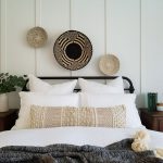 posteľ v boho štýle s vankúšmi a pletenými prírodnými dekoráciami zavesenými nad čelom postele