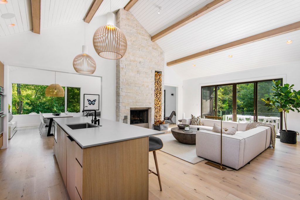 Otvorený priestor kuchyne, jedálne a obývačky, v bielej a sivej farbe v kombinácii s drevom, v minimalistickom štýle