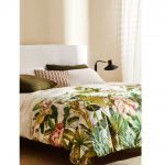 Interiérové trendy roka 2021: posteľ s bavlnenými obliečkami s tropickým motívom