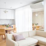 interiér obývačka prepojenej s kuchyňou v jemných pastelových a svetlých farbách a v minimalistickom škandinávskom dizajne, s nadrozmerným zrkadlom, ktoré opticky zväčšuje miestnosť