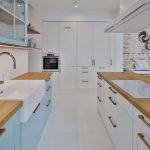moderná vidiecka kuchyňa v novostavbe, s nábytkom v bielej a pastelovej modrej, s kazetovými dvierkami, keramickým umývadlom a ostrovčekom