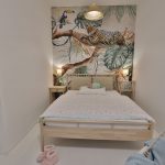 detská izba so svetlou drevenou posteľou a tapetou džungle