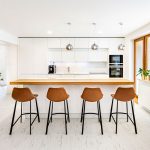 Moderná kuchyňa v bielej farbe s koženými barovými stoličkami
