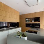 moderná kuchyňa z dubovej dyhy, s výsuvnou zástenou na uskladnenie kuchynských spotrebičov a tajným vstupom do komory vedľa zabudovanej chladničky