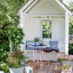 romantický biely záhradný prístrešok s terasou a kvetinami