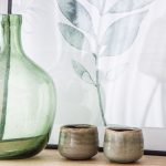 zátišie so zelenou sklenenou vázou, dvomi keramickými miskami a obrazom s motívom listu