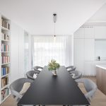 minimalistický interiér s čiernym jedálenským stolom, bielou kuchyňou s ostrovom a úložnými priestormi s otvorenou knižnicou