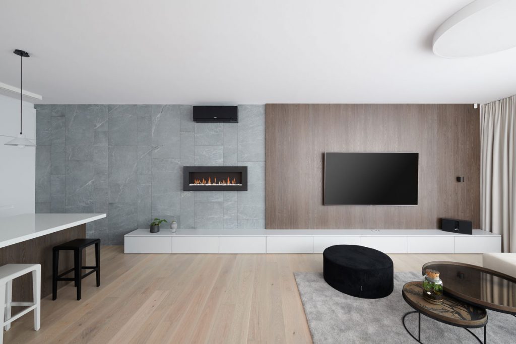 otvorený priestor modernej obývačky s kuchyňou zariadený v minimalistickom štýle, s kamenným a dreveným obkladom na stene, podlahou z bieleho dubu a biokrbom