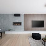 otvorený priestor modernej obývačky s kuchyňou zariadený v minimalistickom štýle, s kamenným a dreveným obkladom na stene, podlahou z bieleho dubu a biokrbom