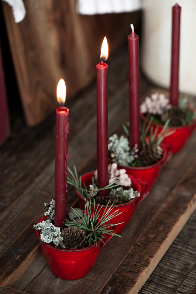 Adventné svietniky vyrobené z červených šálok a naaranžované s prírodninami a sviečkami