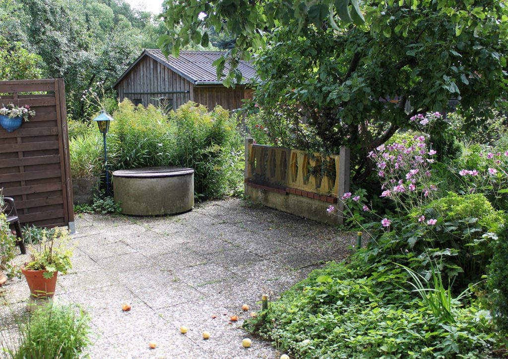 Menšia záhrada s terasou, okrasnými záhonmi a stromom