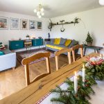 obývačka v retro vidieckom štýle so sivou pohovkou, modrou retro komodou so starým rádiom, a vianočne prestretým jedálenským stolom