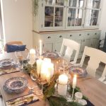 Slávnostne prestretý vianočný stôl so svietnikmi, čečinou a elegantnými taniermi s vidieckym vzorom