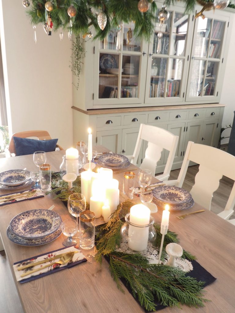 Slávnostne prestretý vianočný stôl so svietnikmi, čečinou a elegantnými taniermi s vidieckym vzorom