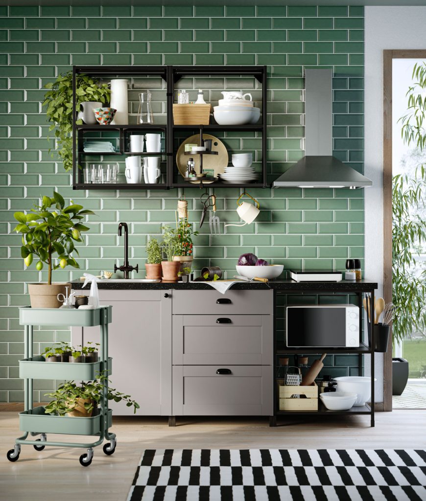 Interiér kuchyne so zeleným obkladom, čiernou regálovou policou a spodnými sivými skrinkami 
