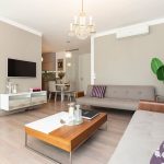 interiér minimalisticky elegantnej obývačky so sivými dizajnovými sedačkami, dreveným konferenčným stolom, živou kvetinou a krištáľovým extravagantným lustrom