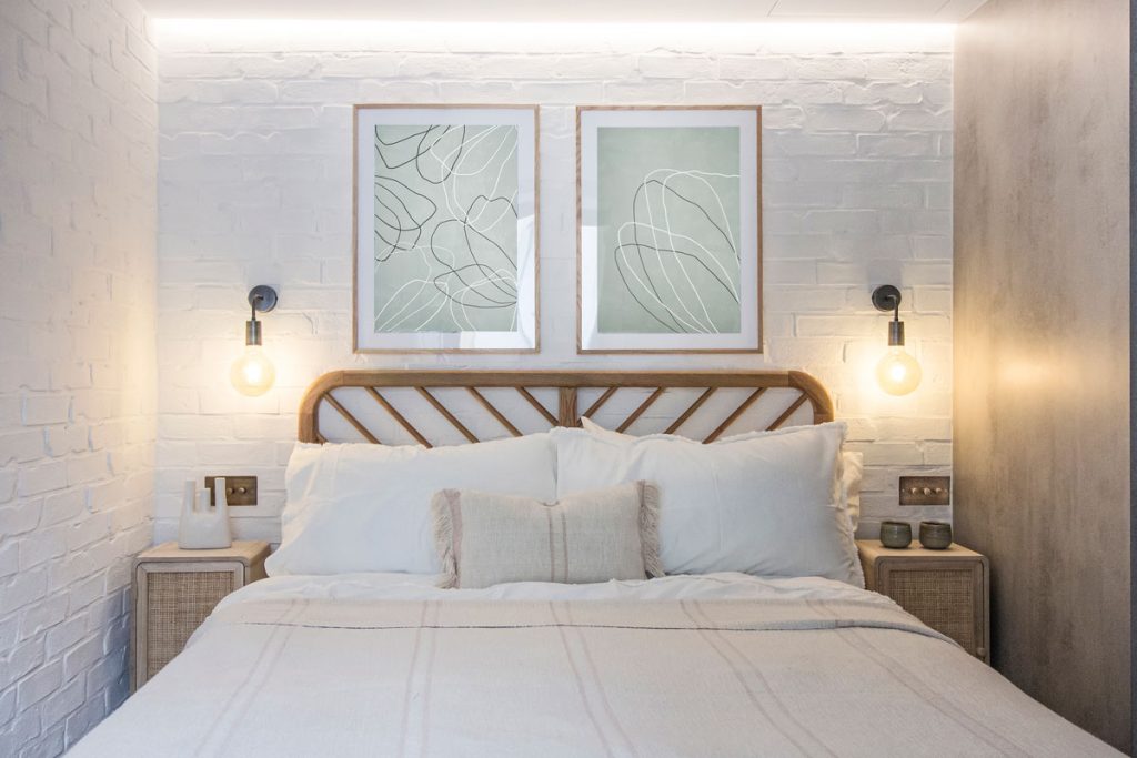 Menšia spálňa s drevenou posteľou, nočnými stolíkmi a bielou tehlovou stenou-(13)
