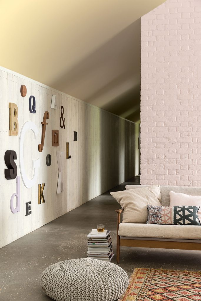 Interiér s bielou tehlovou stenou a stenou s bielym dreveným obkladom s dekoráciami písmen
