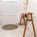 kúpeľňa so vzorovanou podlahou a drevenou lavičkou na uteráky
