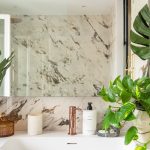 elegantná kúpeľňa s keramikou s mramorovým vzorom a medenou batériou, interiér je doplnený o zelené rastliny