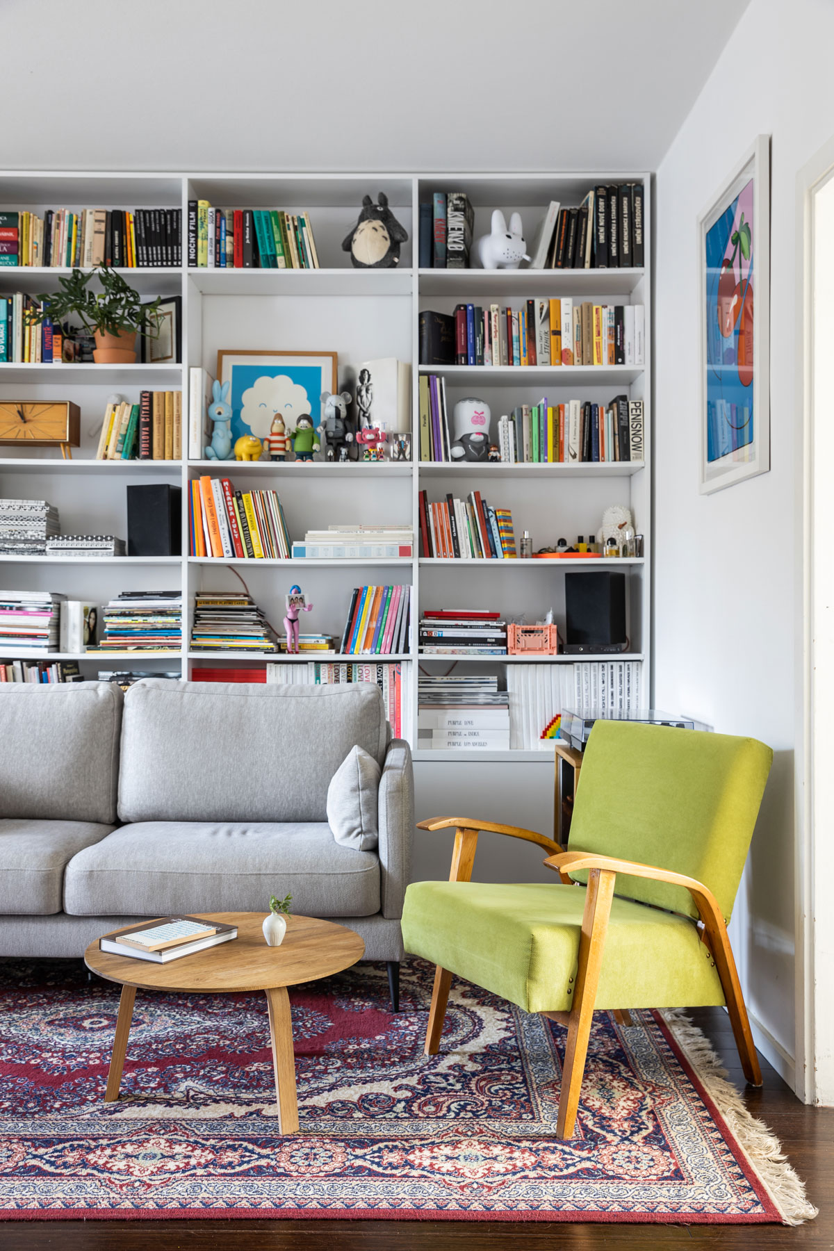 Detail obývačky so zeleným kreslom, sivou sedačkou a knižnicou