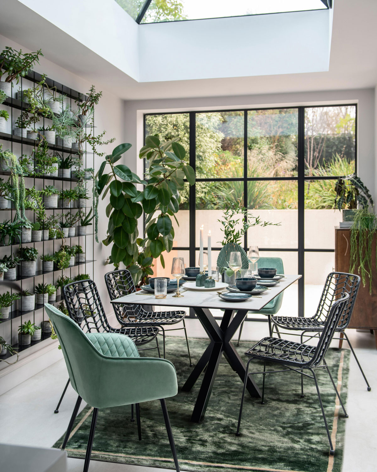 Jedáleň s čalúnenými kresielkami, vertikálnou stenou s kvetinami a presklenou stenou s výhľadom na terasu, celý priestor je ladený v tónoch zelenej
