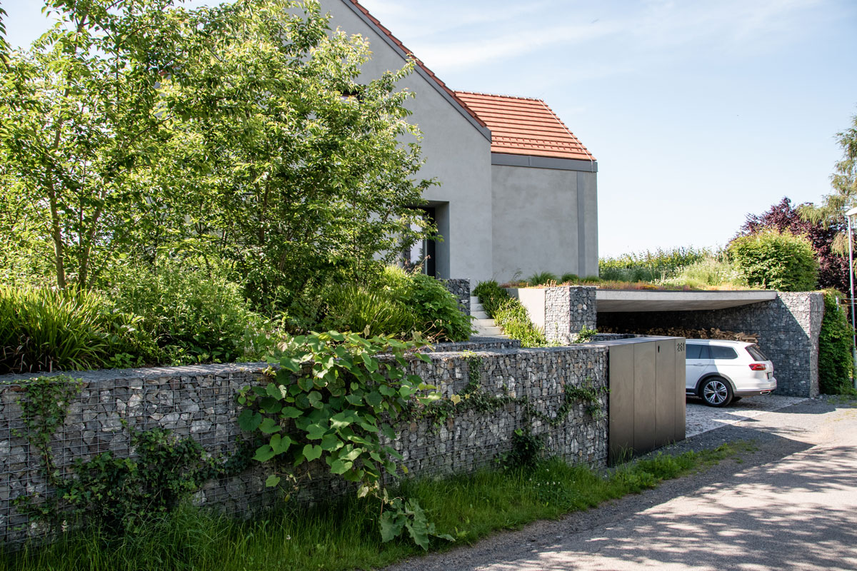 exteriér rodinného domu s gabiónovým múrom, čerešňovým hájikom a garážou so zelenou vegetačnou strechou