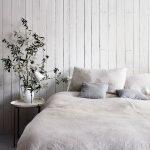 jednoduchá spálňa v scandi vidieckom štýle s dreveným bielym obkladom na stene za posteľou