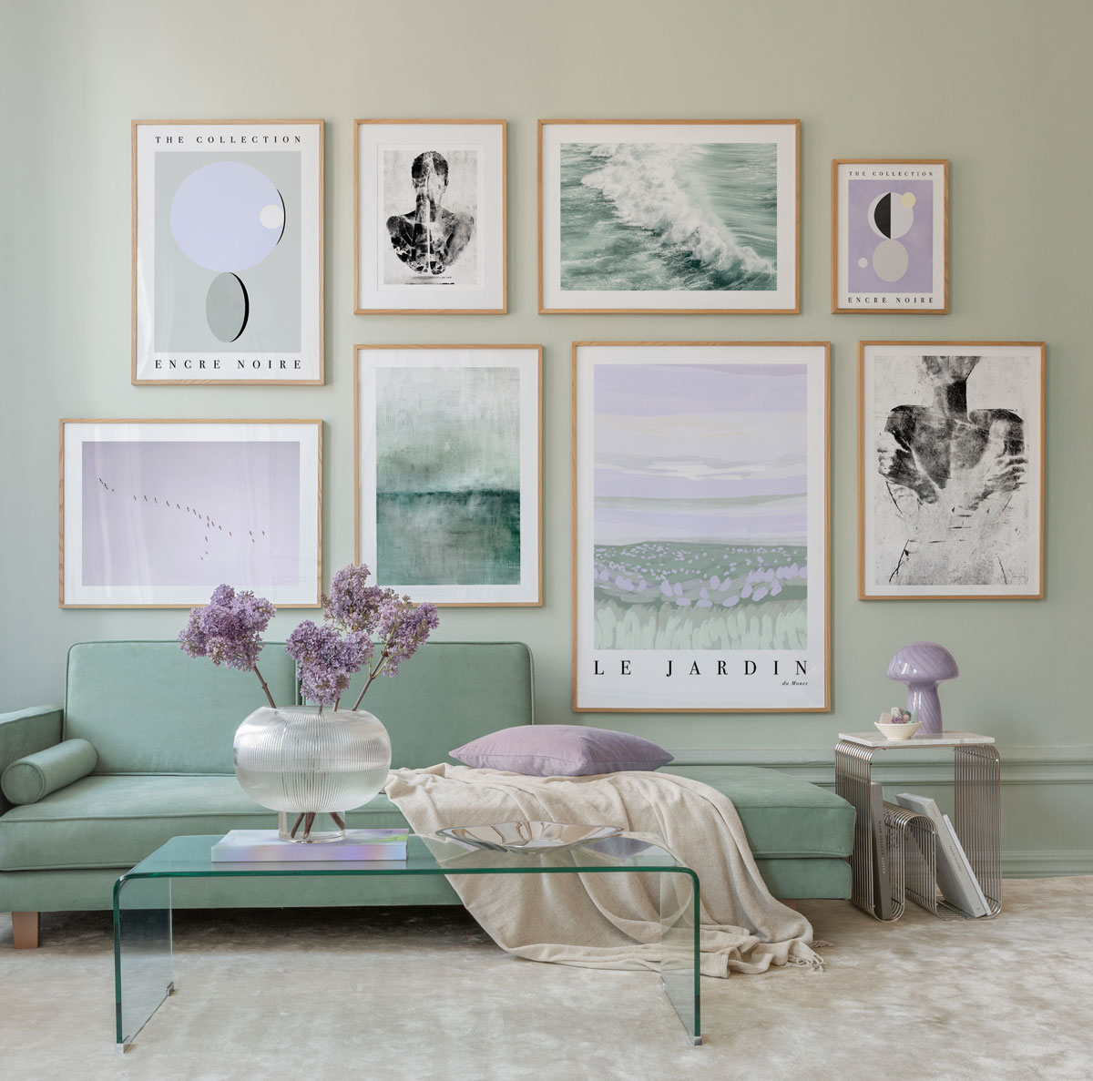 Moderná obývačka s minimalistickou zelenou sedačkou, skleneným stolíkom a obrazmi za sedačkou