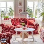 Romantická obývačka s červenou sedačkou a kresielkami s bielym vzorom kvetov, medzi nimi je biely stolík