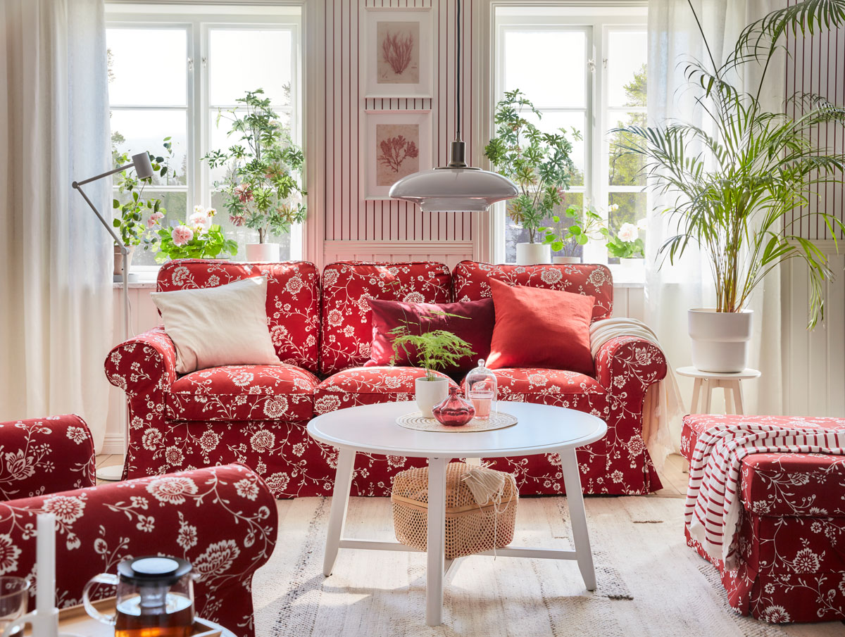 Romantická obývačka s červenou sedačkou a kresielkami s bielym vzorom kvetov, medzi nimi je biely stolík 
