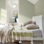 Podkrovná spálňa so zelenými stenami, táto farba sa opakuje aj na posteľnom prádle