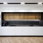 Symetrická kuchyňa v minimalistickom dizajne v bielej farbe, tvorí akoby jeden blok a ukrýva vybavenie kuchyne