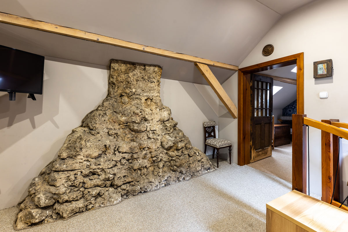 podkrovná miestnosť v drevenici slúžiaca ako herňa s priznaným kamenným komínom