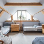 podkrovná spálňa v drevenici s dvoma sivými posteľami vytvorenými zo starých čiel postele