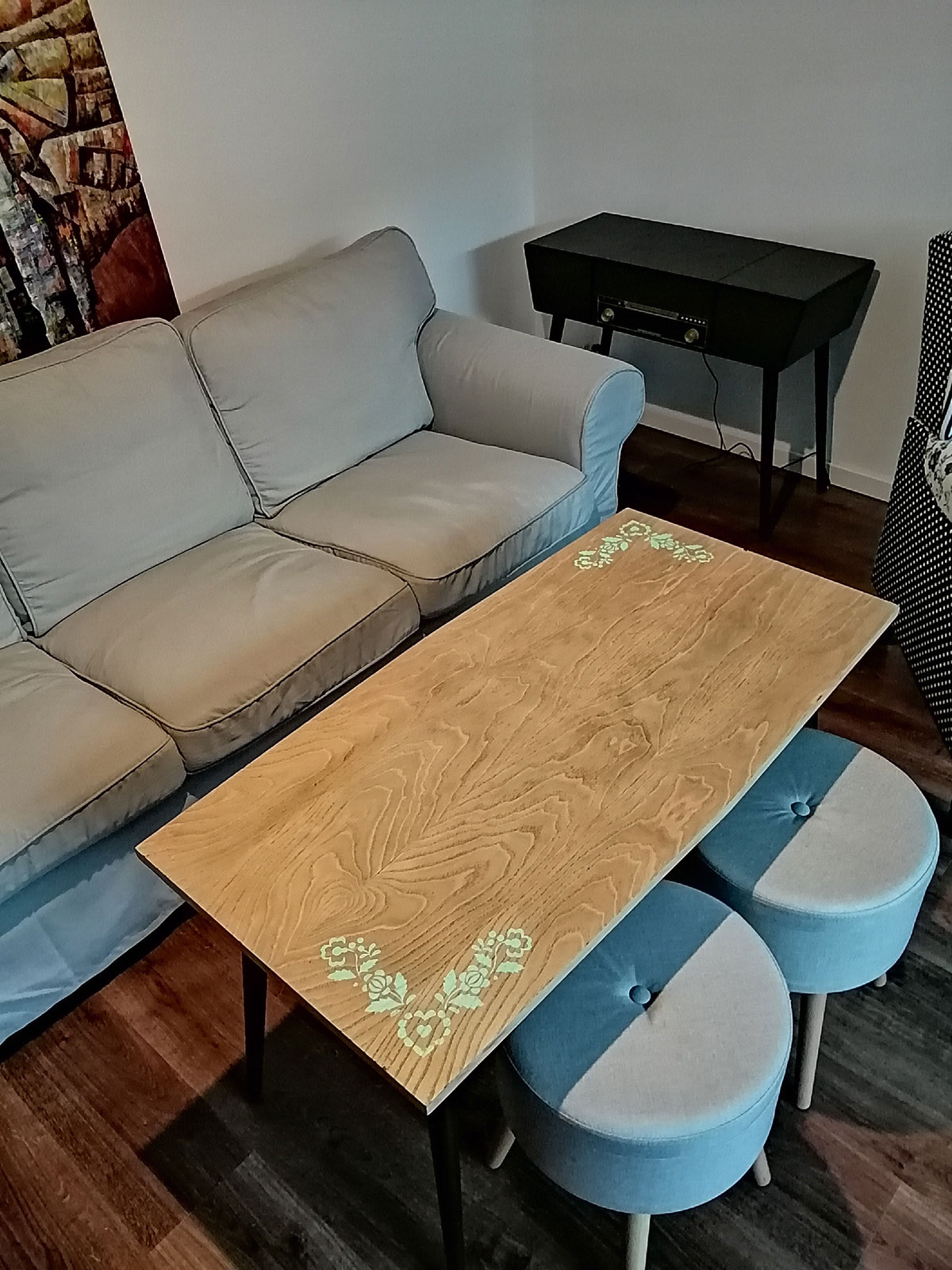 moderná obývačka so sivou sedačkou, taburetmi a zrenovovaným retro stolíkom