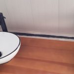 Nanesený čierny silikón medzi stolom a stenou v kúpeľni