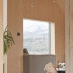 Pohľad do obývačky s dreveným obložením a výhľadom na hory