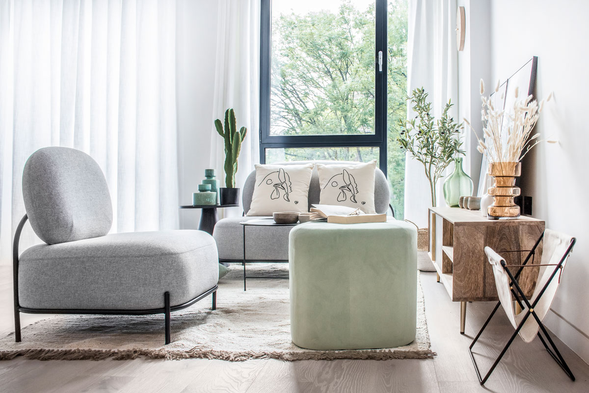 obývačka v neutrálnom dizajne, dve kreslá v sivej farbe s pastelovozeleným taburetom a drevená komoda na nožičkách