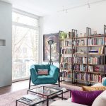 Obývačka s elegantnými modrými kreslami, krbom a veľkou knižnicou