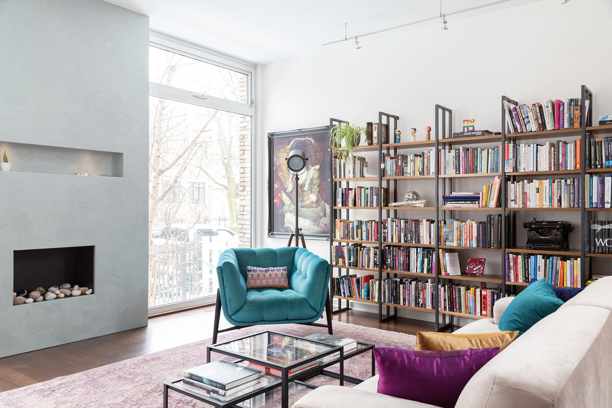 Obývačka s elegantnými modrými kreslami, krbom a veľkou knižnicou
