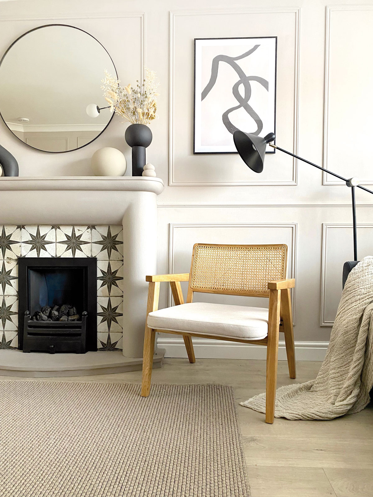 Interiér s dekoračnými lištami na stene, ladený do odtieňov bielej, s drevenou stoličkou a krbom